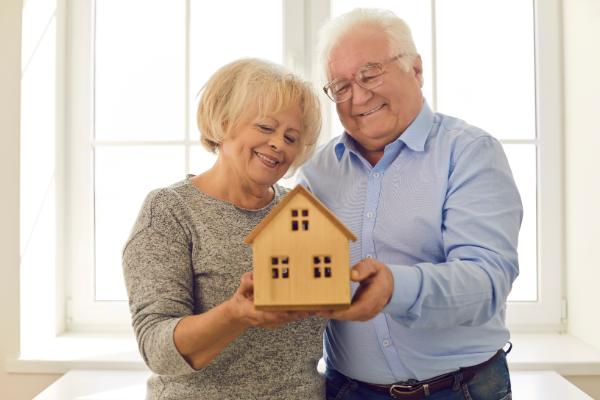 senior couple holding a miniature house